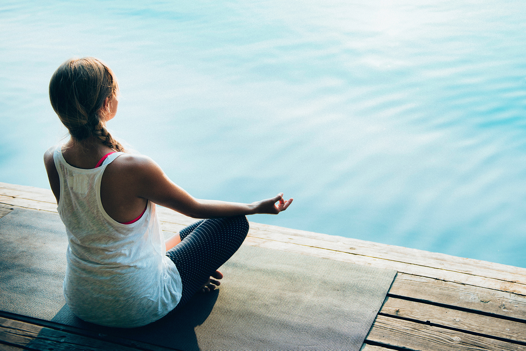 Meditation, water. Young woman meditating by the lake. Calm wate
